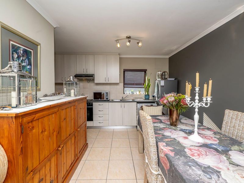 Open-plan kitchen and dining area featuring light-toned cabinetry, tiled flooring, and a functional layout suitable for modern living.