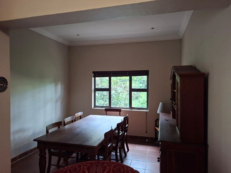 A functional dining room featuring tiled flooring, recessed ceiling lighting, and a window providing natural light and garden views.