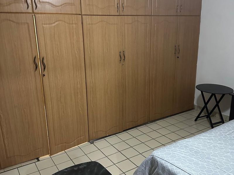 A bedroom featuring extensive built-in wooden cupboards and tiled flooring, offering ample storage space.