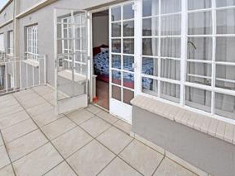 A tiled balcony featuring metal railings and direct access to the interior through classic french doors and multi-pane windows.