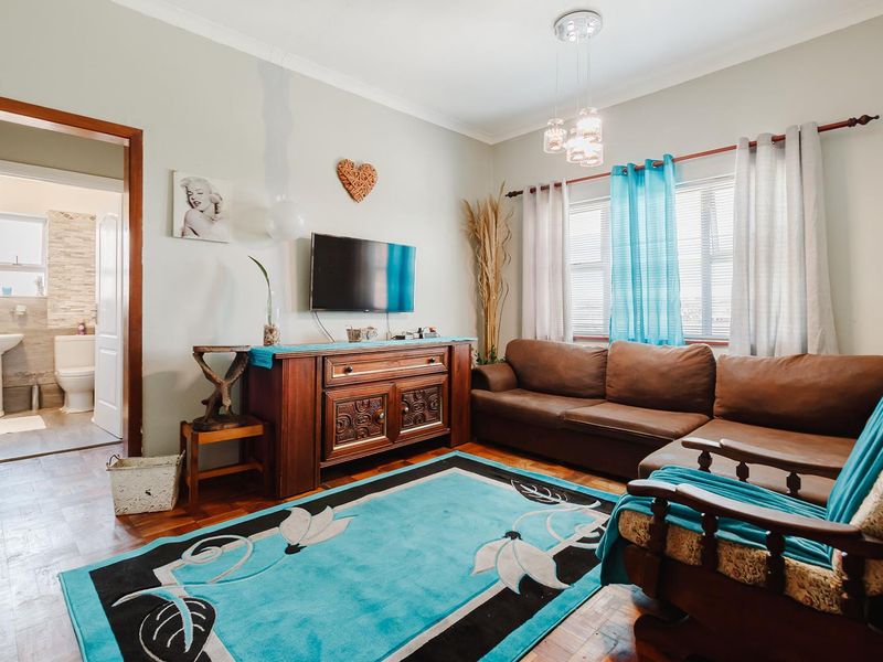 A cozy living room featuring parquet flooring, coved ceilings, and a view into the adjacent bathroom.