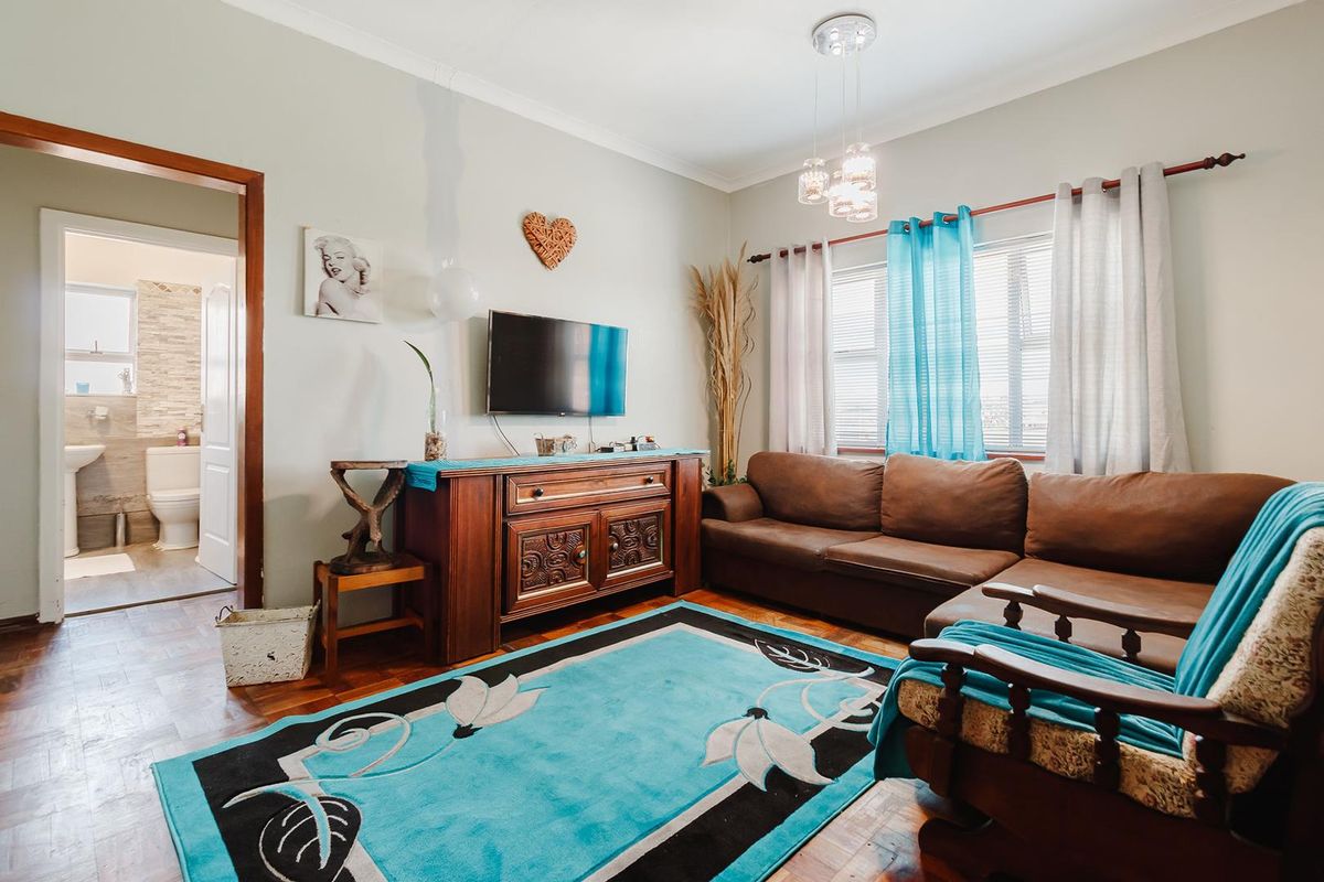 A cozy living room featuring parquet flooring, coved ceilings, and a view into the adjacent bathroom.
