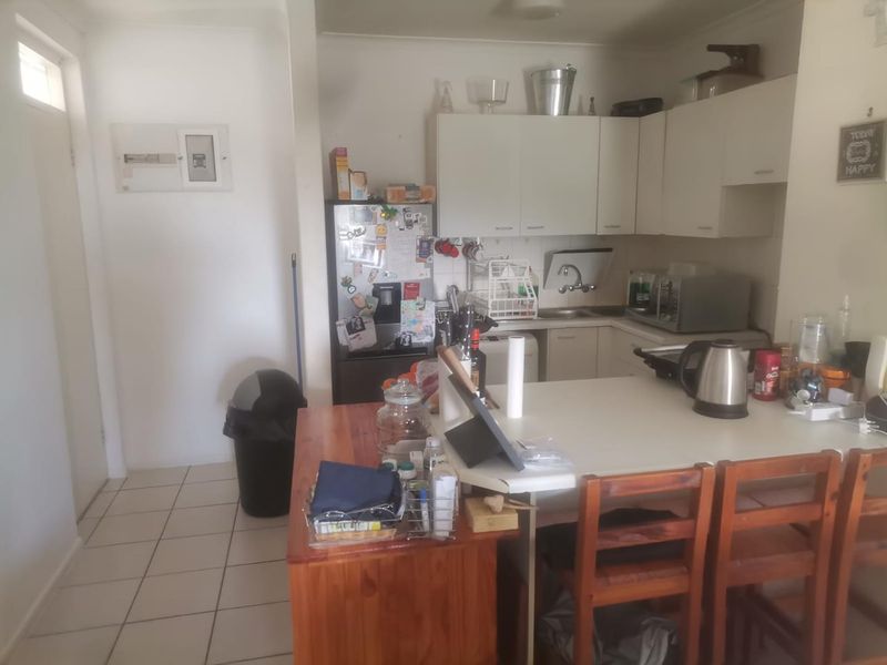 A functional kitchen area featuring built-in cabinetry, laminate countertops, a stainless steel sink, and tiled flooring, with an integrated breakfast bar.
