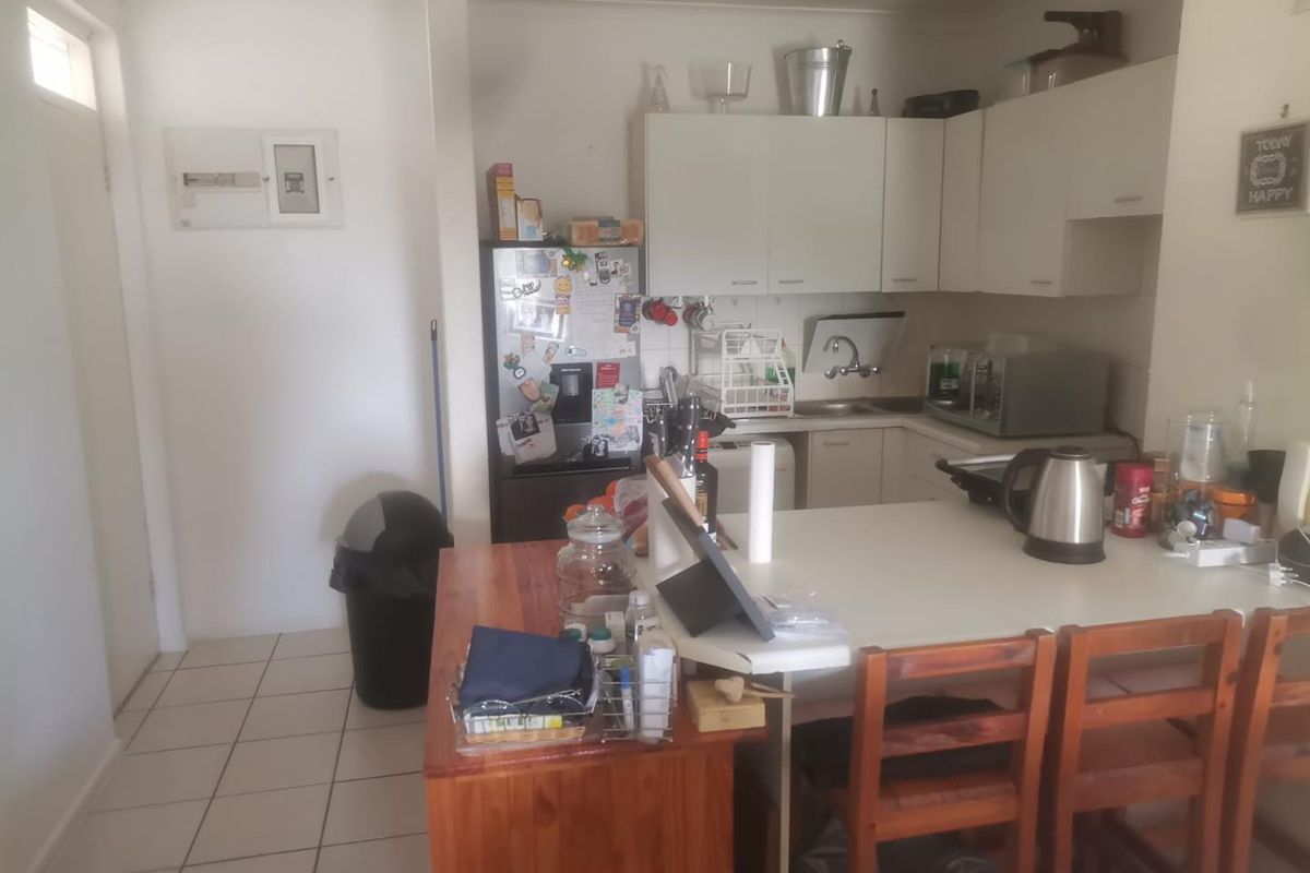 A functional kitchen area featuring built-in cabinetry, laminate countertops, a stainless steel sink, and tiled flooring, with an integrated breakfast bar.