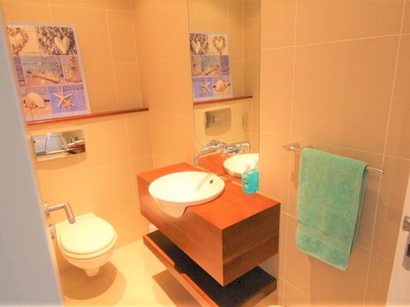 A modern bathroom featuring a floating vanity with a vessel sink, wall-mounted faucet, and a wall-hung toilet with neutral wall tiling.