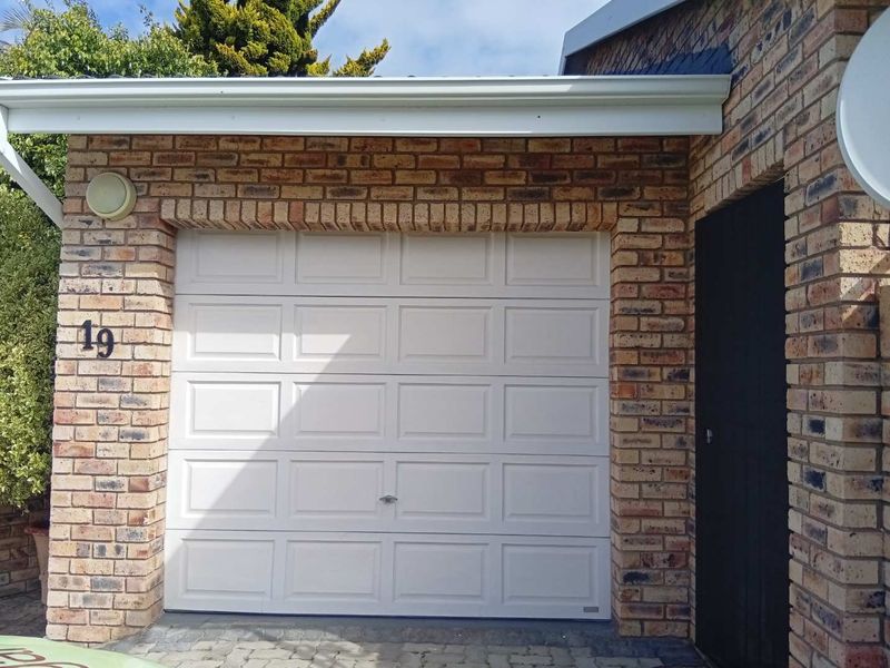 A well-maintained single garage featuring a white sectional door and classic face brick exterior finish.