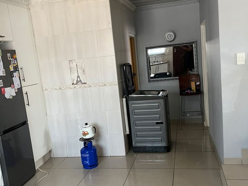 A functional kitchen area featuring tiled flooring, built-in cabinetry, and a tiled splashback with a coved ceiling finish.