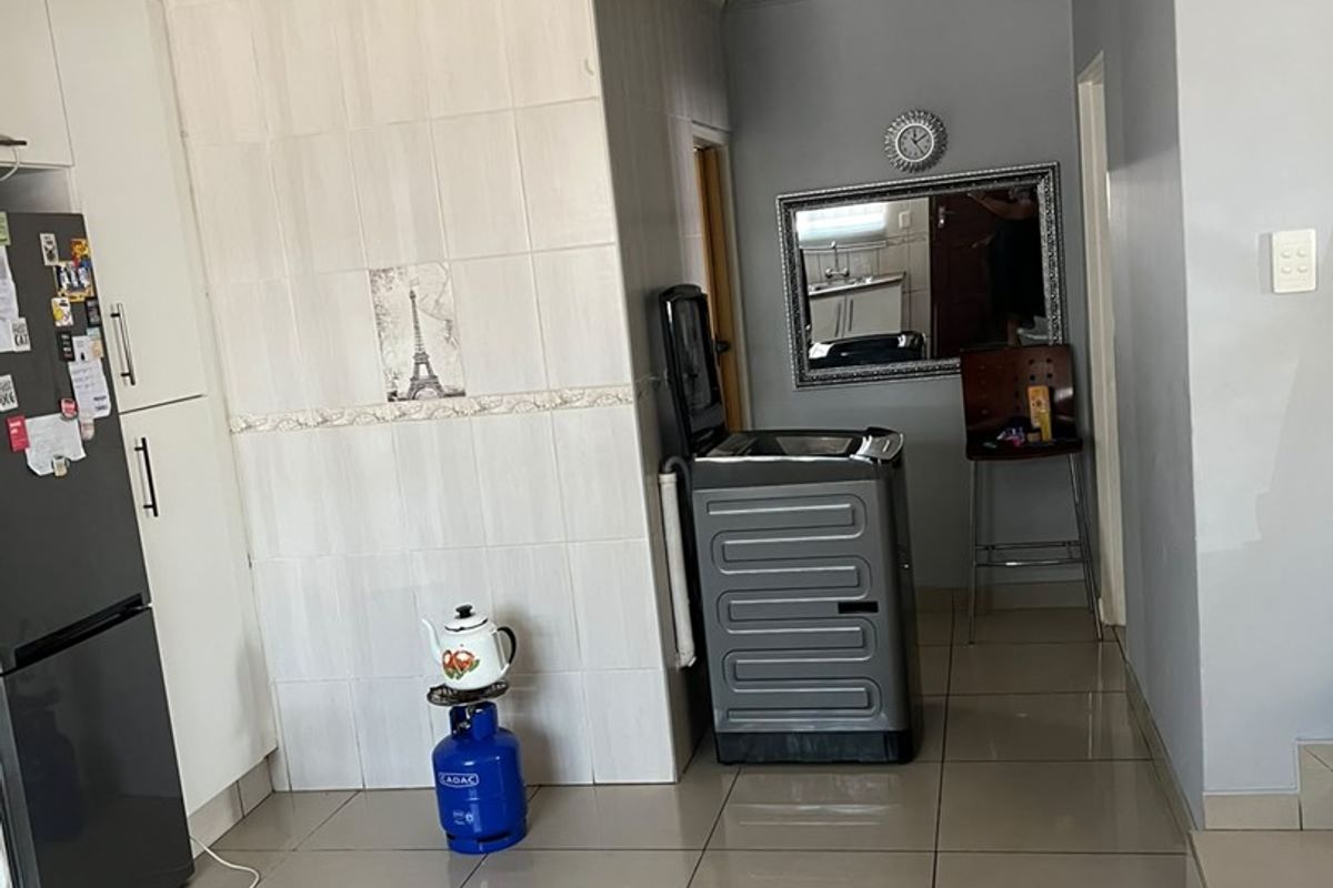 A functional kitchen area featuring tiled flooring, built-in cabinetry, and a tiled splashback with a coved ceiling finish.