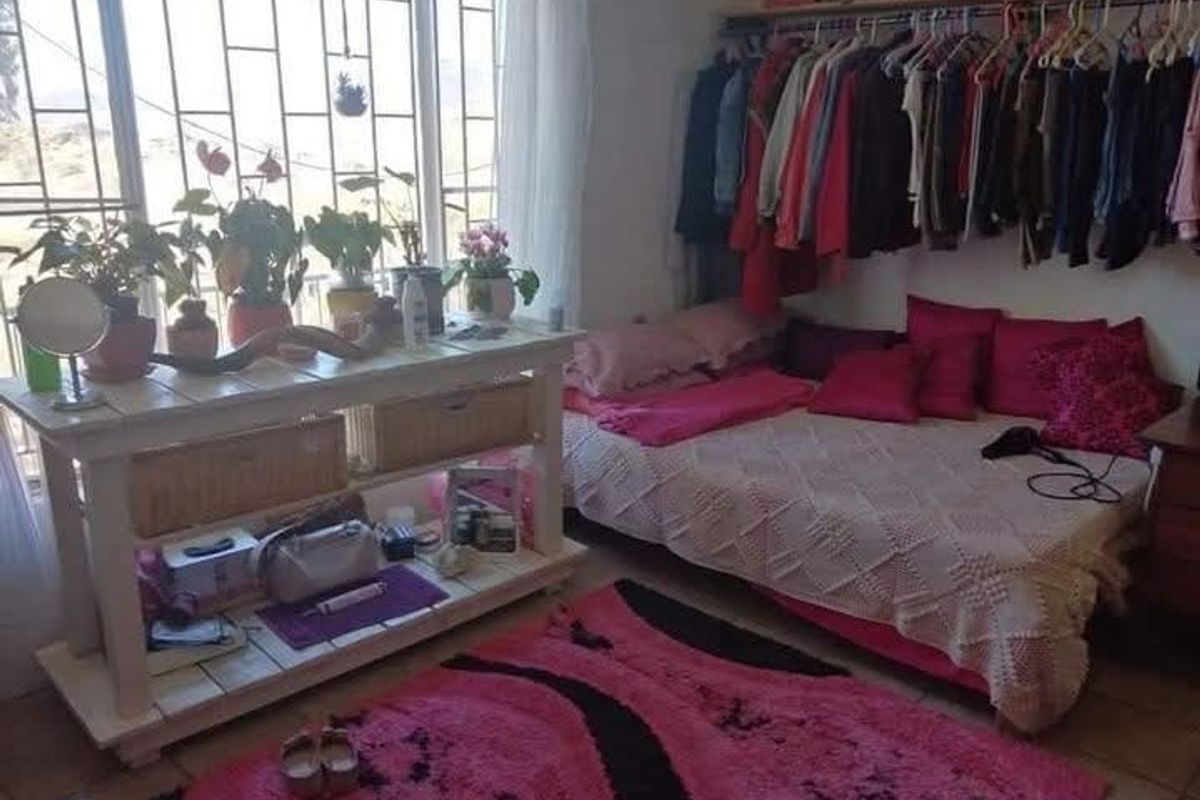 A bedroom featuring large windows with security bars, tiled flooring, and an open-concept closet storage area.