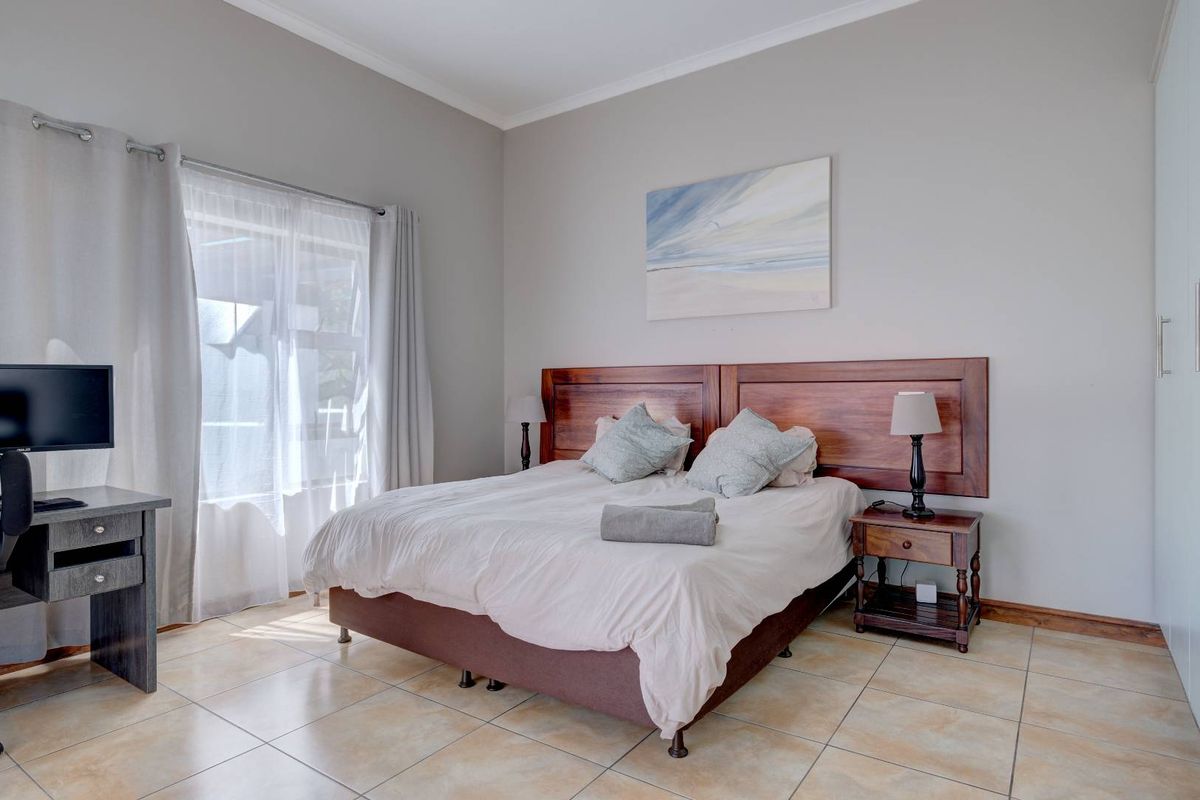 A well-maintained bedroom featuring neutral wall tones, tiled flooring, and a built-in wooden headboard, offering a clean and comfortable living space.