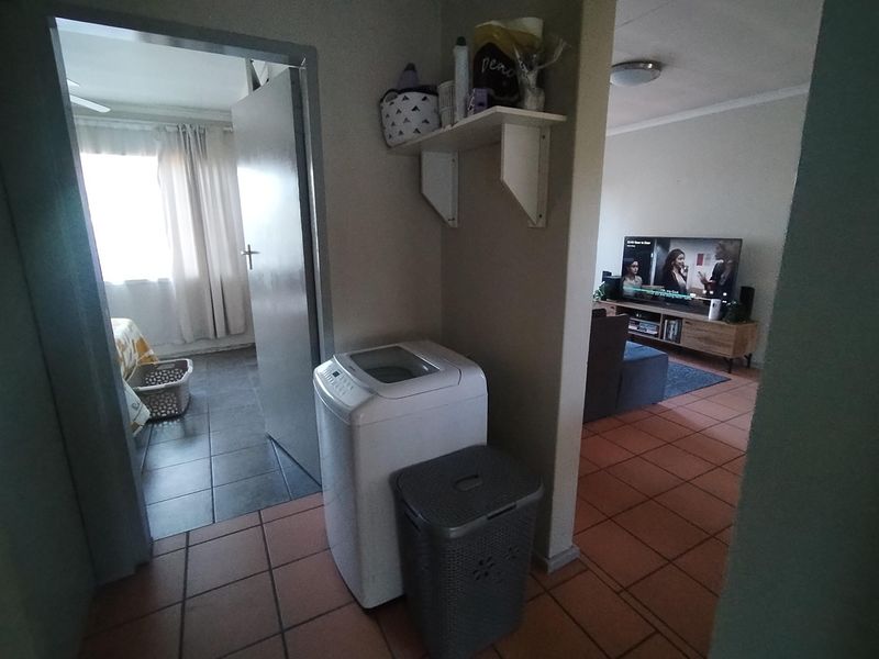 A functional hallway area featuring tiled flooring and wall-mounted shelving, providing access to adjacent living and bedroom spaces.