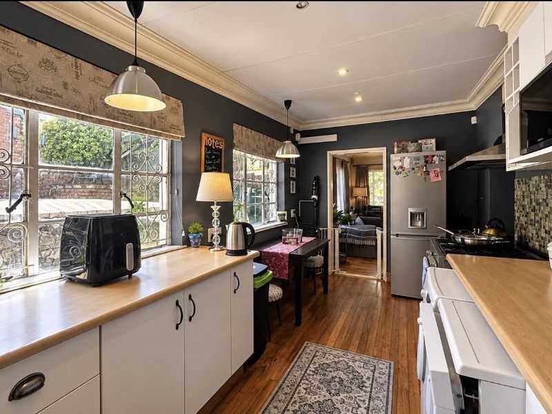 A well-maintained kitchen featuring dark cabinetry, mosaic tile backsplash, laminate countertops, hardwood flooring, and integrated appliances with ample natural light.