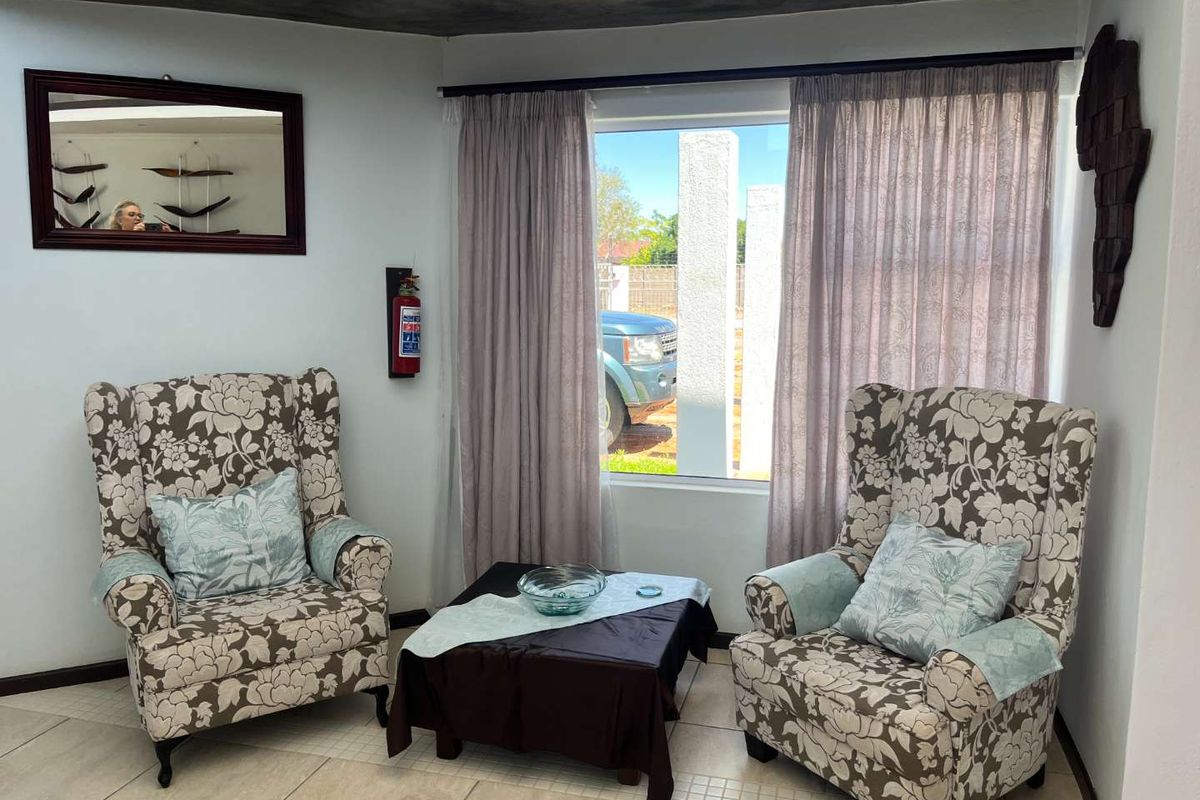 A cozy seating area featuring tiled flooring, recessed ceiling lighting, and a wall-mounted fire extinguisher, with natural light entering through a large window.
