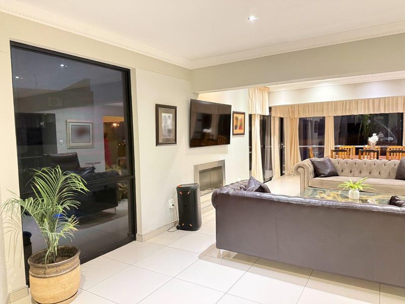 Spacious living area featuring tiled flooring, recessed lighting, crown molding, and a modern built-in fireplace with large sliding glass doors.