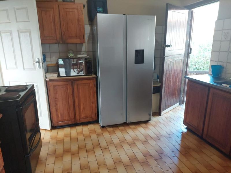 A functional kitchen featuring wooden cabinetry, tiled flooring, and a tiled backsplash, with direct access to the exterior.