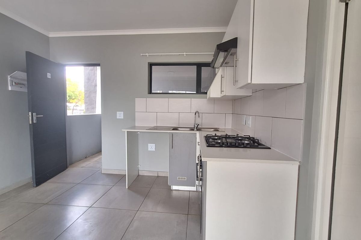 Modern kitchen featuring built-in cabinetry, a gas hob with extractor fan, stainless steel sink, and neutral tiled flooring.