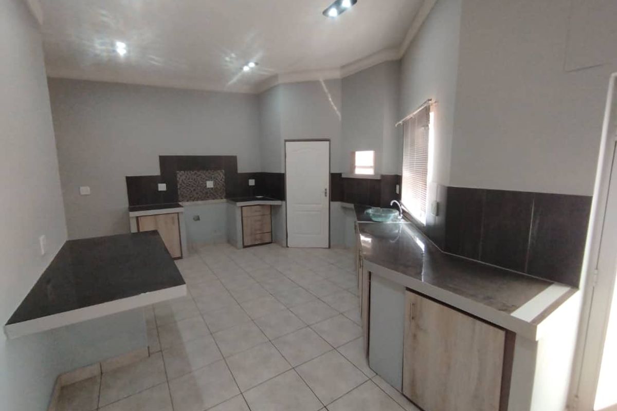 A functional kitchen space featuring dark countertops, tiled splashbacks, and built-in cabinetry with some open shelving areas.