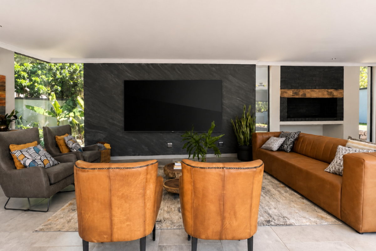 Modern living room featuring a striking stone feature wall with a built-in fireplace, tiled flooring, and recessed lighting, creating a sophisticated and comfortable atmosphere.