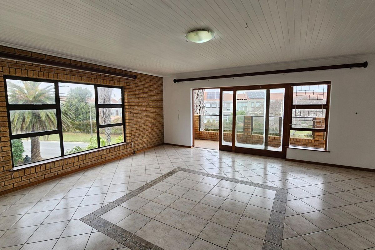 Spacious living area featuring exposed brick feature walls, large windows, and sliding glass doors leading to an outdoor patio space.