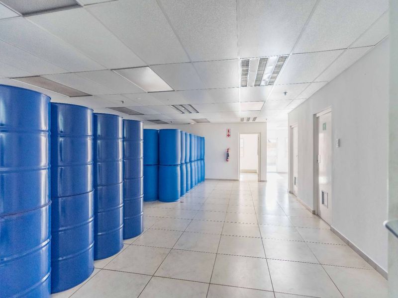 A clean industrial utility space featuring tiled flooring, a suspended ceiling with recessed lighting, and multiple internal access doors.