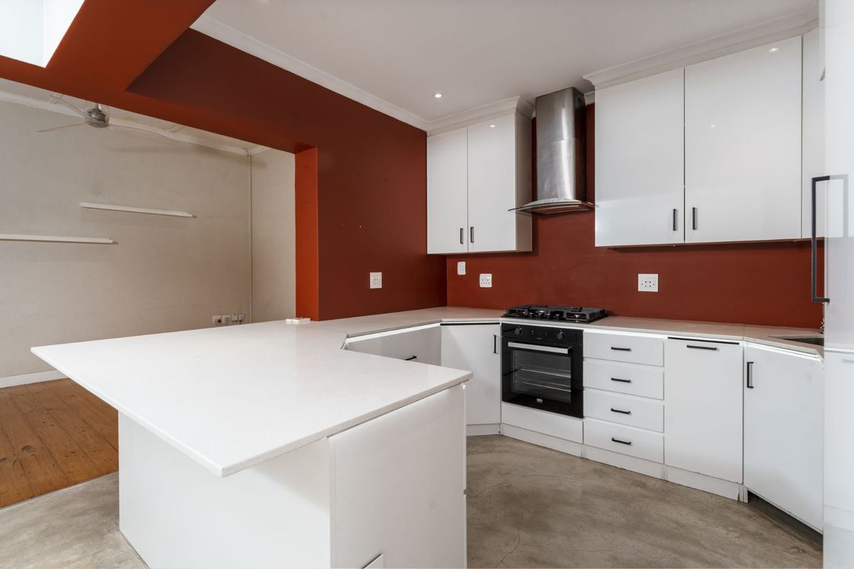 A modern kitchen featuring white cabinetry, quartz countertops, a built-in oven with gas hob, and polished concrete flooring.