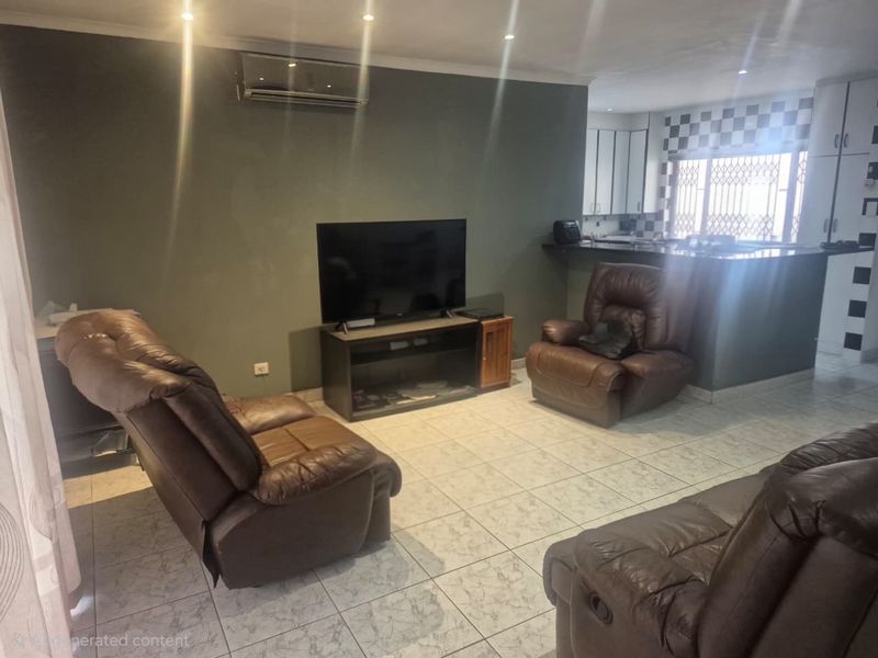 Open-plan living area featuring tiled flooring, recessed lighting, and a connected kitchen with breakfast bar and built-in cabinetry.