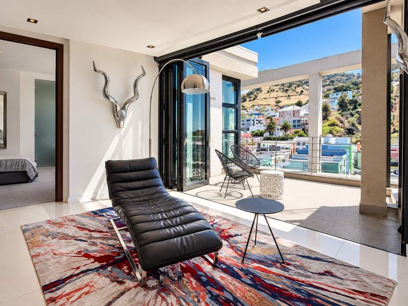 Modern living area featuring large bi-fold doors opening onto a balcony with scenic urban and mountain views, finished with high-quality tiled flooring.