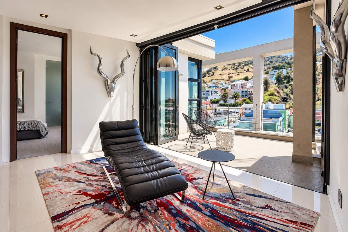 Modern living area featuring large bi-fold doors opening onto a balcony with scenic urban and mountain views, finished with high-quality tiled flooring.