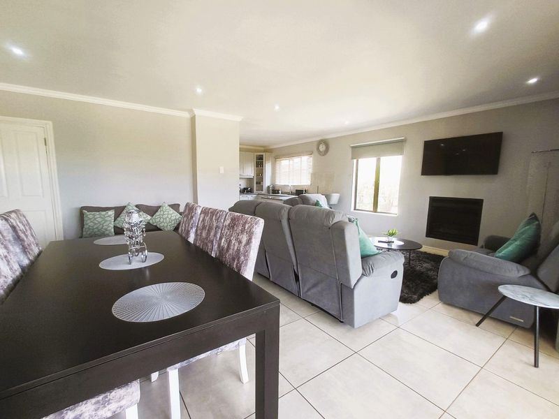 Spacious open-plan living and dining area featuring tiled floors, recessed lighting, and a built-in fireplace, seamlessly connected to the kitchen.