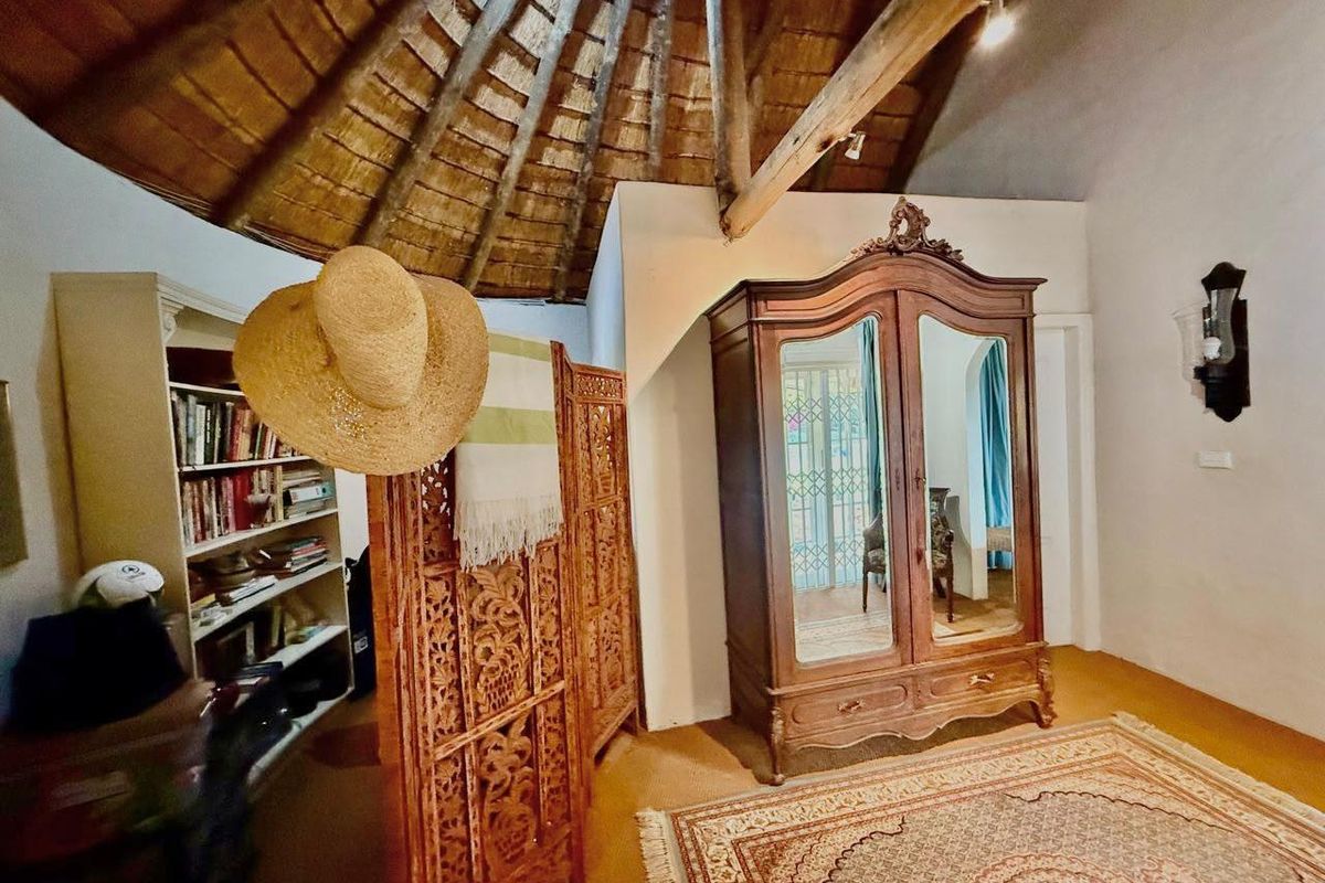 Bedroom featuring a traditional thatched roof with exposed timber rafters and a secure metal gate leading to the exterior.