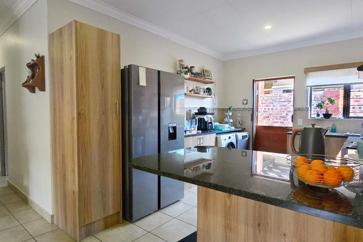A functional kitchen featuring wood-look cabinetry, dark granite countertops, a breakfast bar, and direct access to an outdoor area.