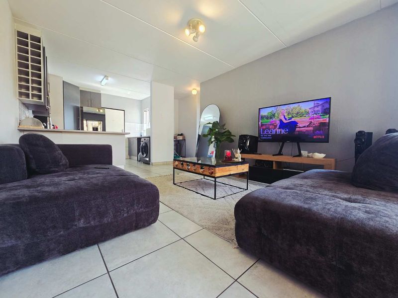 Open-plan living area featuring tiled flooring and a functional kitchen with built-in cabinetry and a breakfast counter.