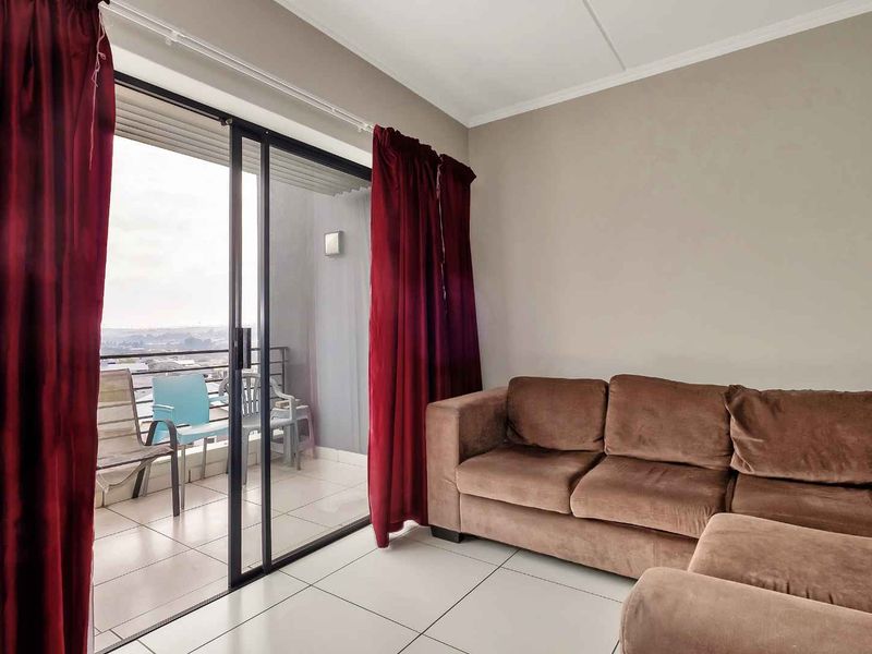 Living room featuring tiled flooring and a large sliding glass door providing direct access to an outdoor balcony area.