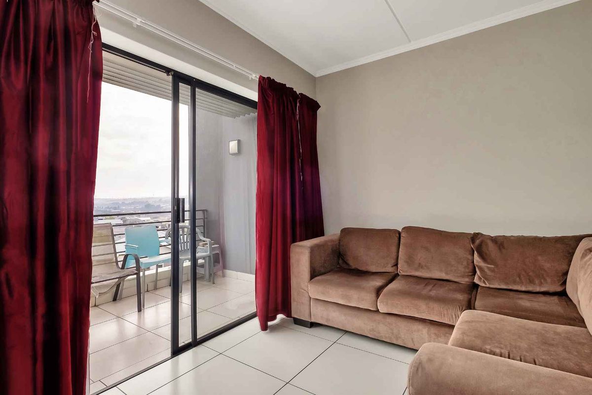 Living room featuring tiled flooring and a large sliding glass door providing direct access to an outdoor balcony area.