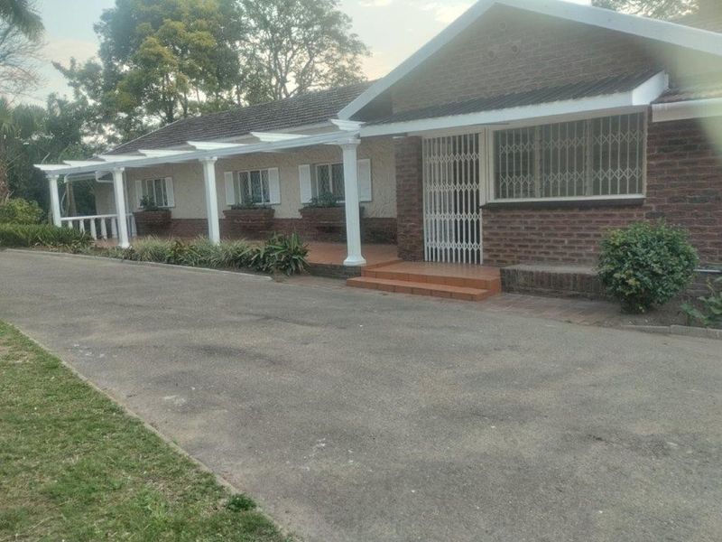 Front exterior view of a brick townhouse featuring a covered patio, security gates, and an asphalt driveway.