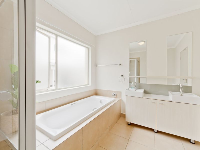 A bright and clean bathroom featuring a built-in bathtub, a double vanity with twin sinks, and a separate shower enclosure with tiled flooring.