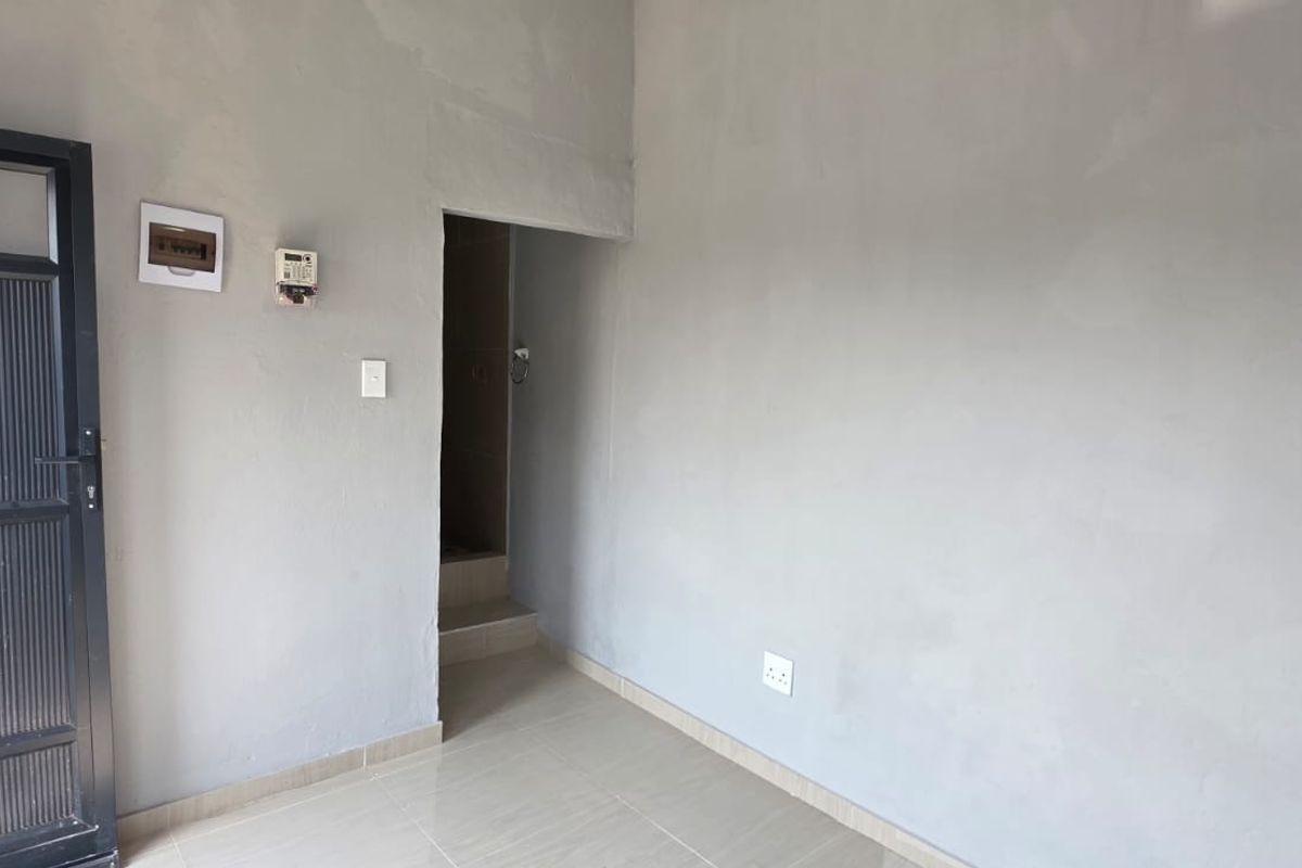 An empty, unfinished living area featuring tiled flooring, exposed plaster walls, and integrated electrical infrastructure, ready for final finishes and interior design.