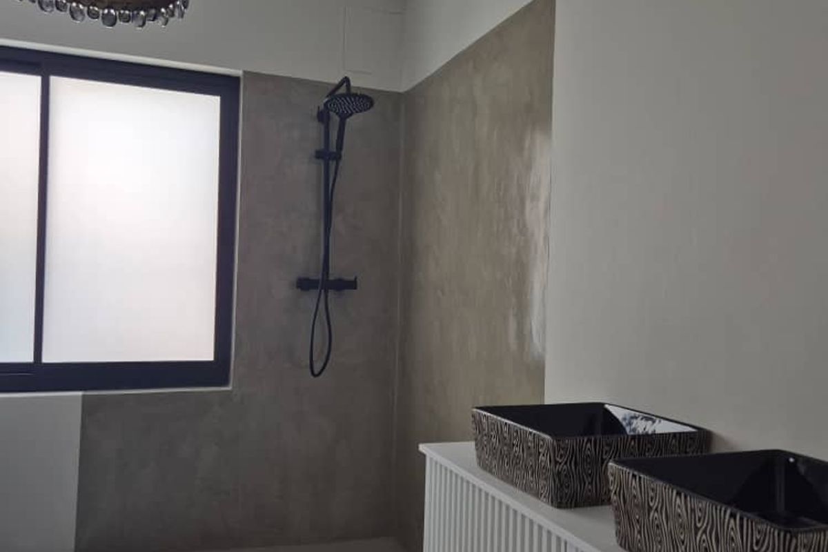 Modern bathroom featuring a walk-in shower with cementitious finishes, double vanity, and contemporary black fixtures.