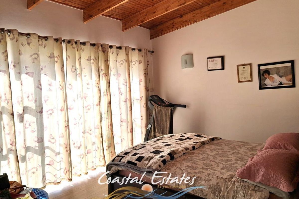 A bedroom featuring exposed timber ceiling beams and a large sliding glass door providing natural light.