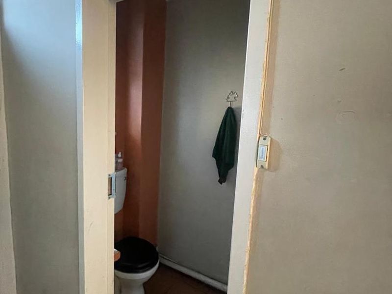 A small, functional bathroom featuring a toilet and tiled flooring, currently in need of cosmetic updates and finishing touches.
