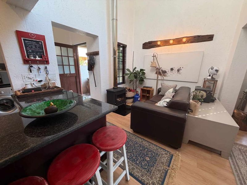 Open-plan living area featuring a granite breakfast bar, wood-burning fireplace with stainless steel flue, and laminate flooring, creating a cozy and functional space.
