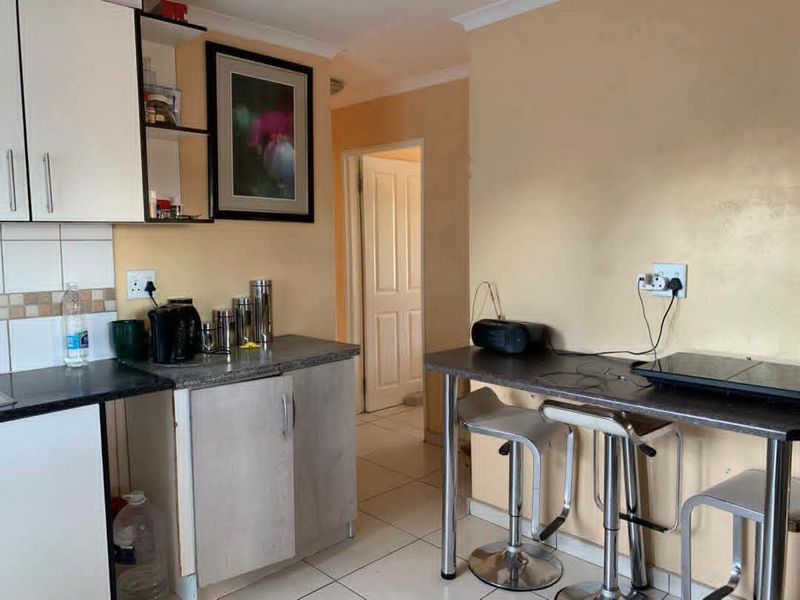Compact kitchen featuring laminate cabinetry, tiled backsplash, and a breakfast bar area with tiled flooring.