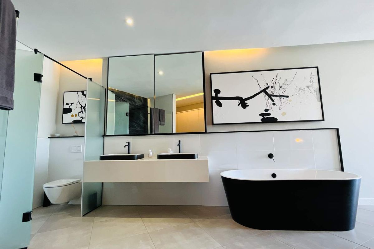Modern luxury bathroom featuring a sleek double vanity, freestanding bathtub, wall-mounted toilet, and high-end contemporary finishes with integrated lighting.