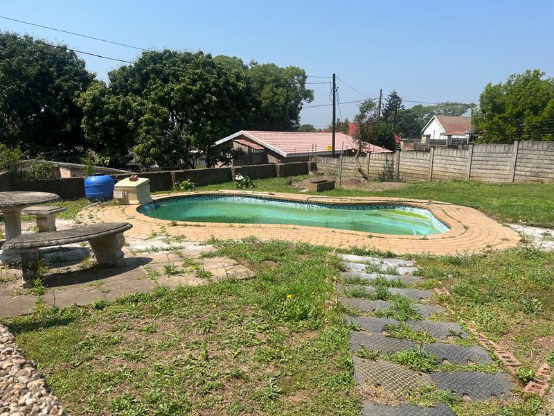 Outdoor pool area featuring a swimming pool with brick paving and perimeter wall, currently requiring maintenance and landscaping.