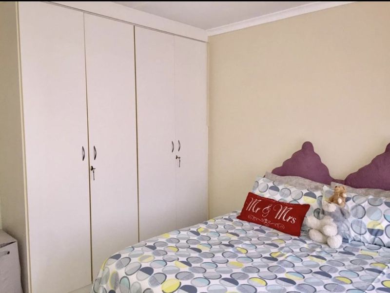 A bedroom featuring neutral walls and floor-to-ceiling built-in cupboards with white doors.