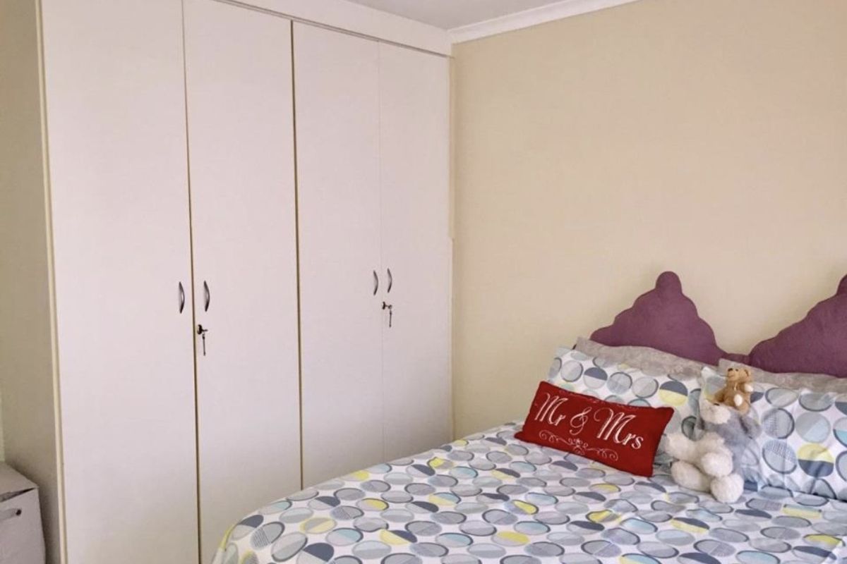 A bedroom featuring neutral walls and floor-to-ceiling built-in cupboards with white doors.