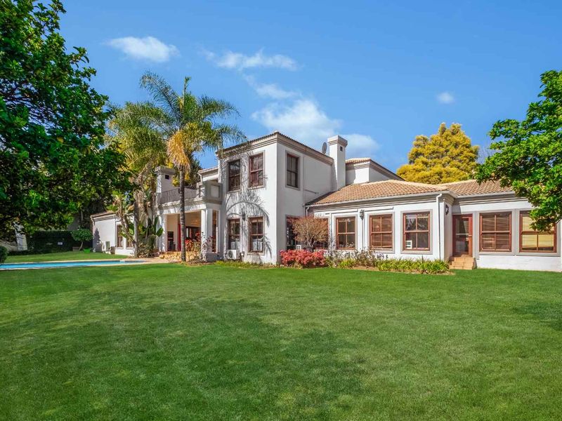Spacious rear exterior view of the house featuring a well-maintained lawn, swimming pool, and a multi-level facade with a balcony.