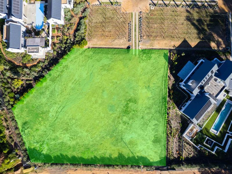 An aerial view of a vacant residential plot, clearly demarcated and situated within a developed estate setting.