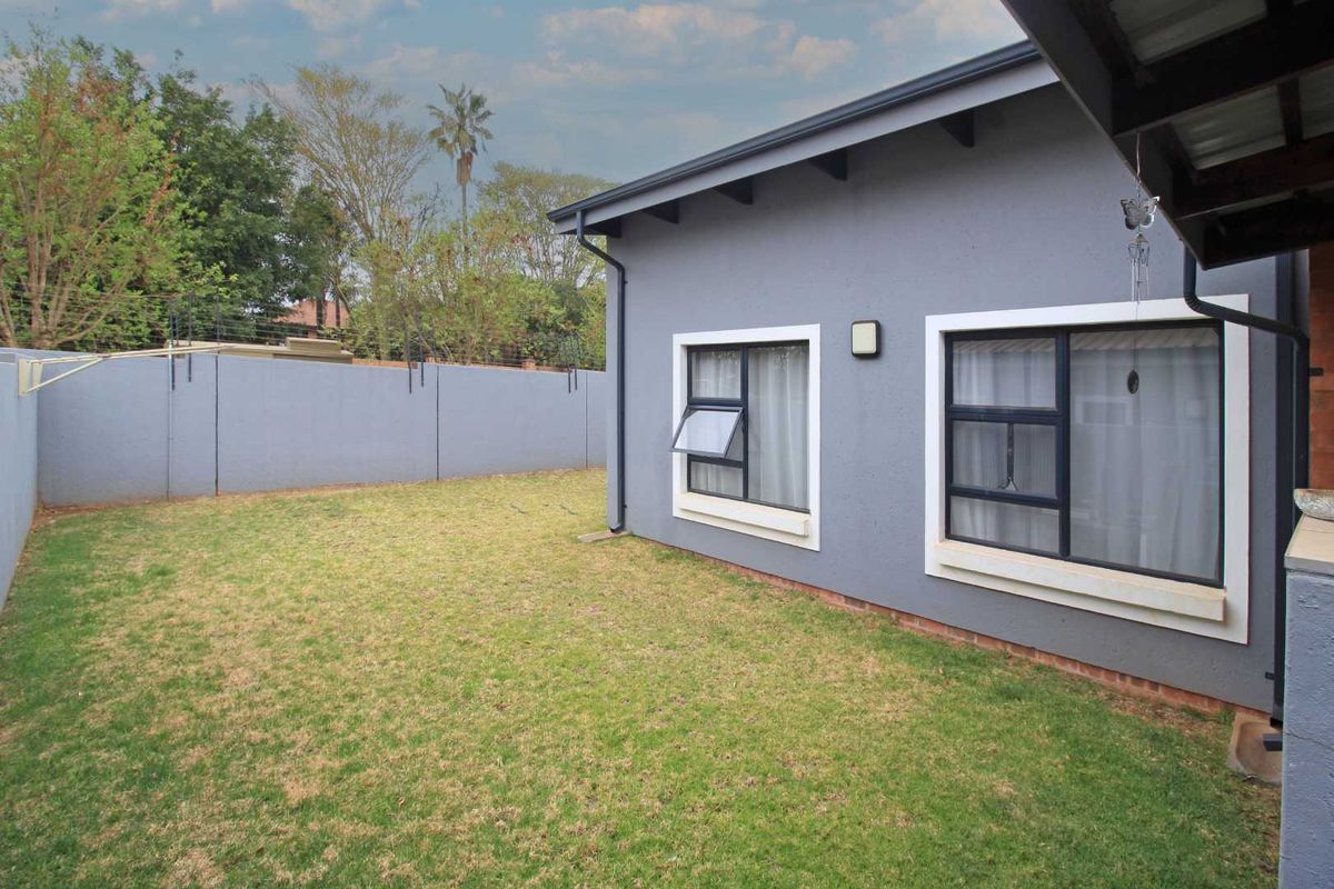 A private rear garden featuring a well-maintained lawn, perimeter boundary wall, and exterior access to the townhouse.