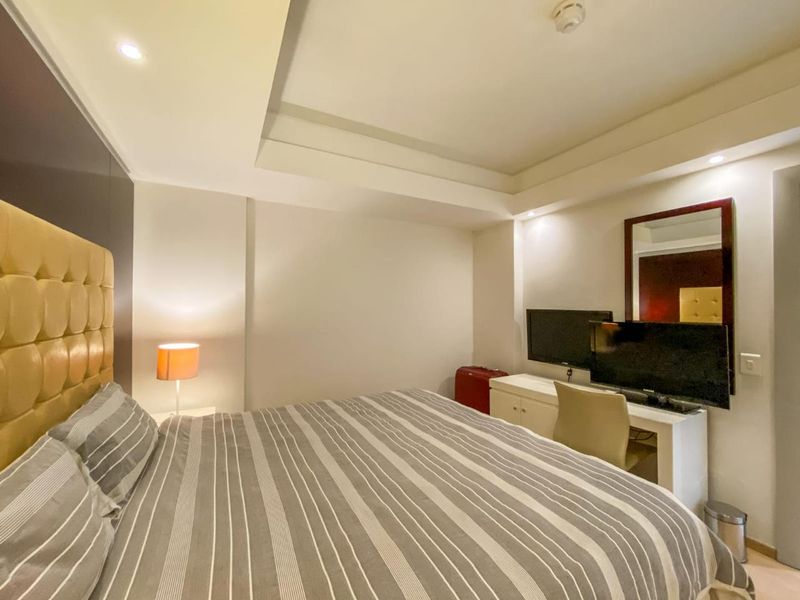 A well-maintained bedroom featuring a recessed ceiling with integrated downlights and a neutral color palette.